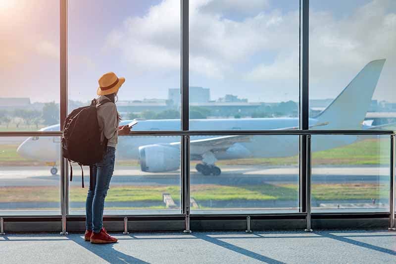 A solo traveler with a backpack looking at a plane on the tarmac, conceptualizing airport transfer and international travel
